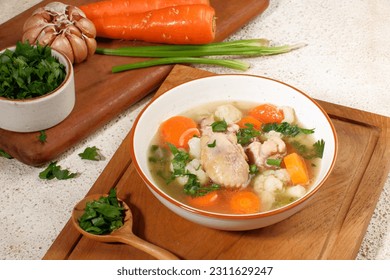 Homemade chicken soup with vegetables in a white bowl.Healthy warm comfortable food. - Shutterstock ID 2311629247