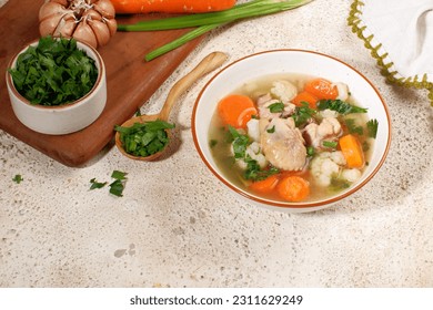 Homemade chicken soup with vegetables in a white bowl.Healthy warm comfortable food. - Shutterstock ID 2311629249