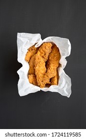 Homemade Chicken Tenders In Paper Box On A Black Surface, Top View. Flat Lay, Overhead, From Above.