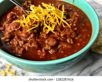 Homemade Chili With Cheese In A Colorful Bowl On White Granite