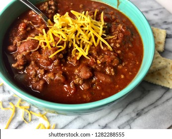 Homemade Chili With Cheese In A Colorful Bowl On White Granite