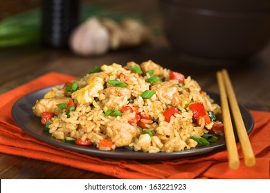Homemade Chinese fried rice with vegetables, chicken and fried eggs served on a plate with chopsticks (Selective Focus, Focus one third into the dish)