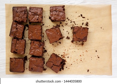 Homemade chocolate brownies on a baking sheet on a white wooden background, top view. Flat lay, overhead, from above. Close-up.