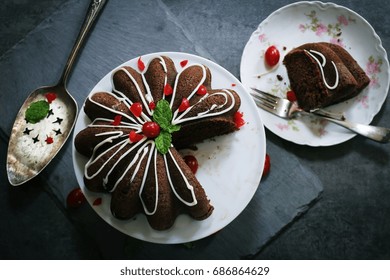 Homemade Chocolate Bundt Cake With A Slice On Plate Against Dark Moody Background, Top Down View