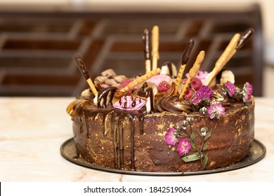 
Homemade Chocolate Cake With Raspberries And Decor Of Flowers And Gold Glitter On Plate