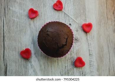 Homemade Chocolate Cupcake Lying On The Wooden Background. Small Heart Candles. Delicious Muffin For Holiday. Flat Lay Food Photo. Valentine's Day Idea For Your Cards Or Social Media.