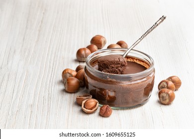 Homemade  chocolate hazelnut praline in glass jar on white wooden table  