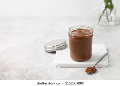 Homemade chocolate in a jar with spoon. Chocolate sauce on white board, tile background. Copy space - Powered by Shutterstock