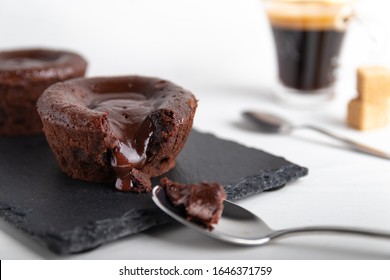 Homemade Chocolate Lava Cake On A Black Plate With A Coffee On A White Background