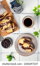 Homemade Chocolate Vanilla Marble Pound Cake With Cup Of Coffee And Cherry Blossoms On White Tile Background. Top View.