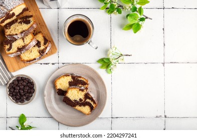 Homemade Chocolate Vanilla Marble Pound Cake With Cup Of Coffee And Cherry Blossoms On White Tile Background. Top View. Space For Text.