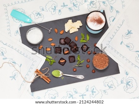 Homemade chocolates with almonds and hazelnuts, without shugar, no preservatives, alternative sweets with stevia, healthy dietary food, with blue cup of coconut milk cappuccino. Top flat view.