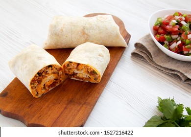 Homemade chorizo breakfast burritos with pico de gallo on a white wooden background, side view. Close-up.