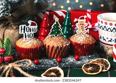 Homemade christmas muffins with fun Christmas signs and christmas decor ornaments on a tablecloth. Christmas sweet concept
