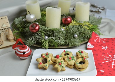 Homemade Christmas sandwich cookies with jam, linzer on the white square plate with Christmas wreath in background - Powered by Shutterstock