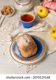 Homemade Cinnamon Bun, Tea In A Vintage Cup On A Linen Tablecloth. Vertical On A Light Wooden Background.