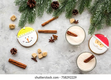 Homemade classic eggnog with cinamon and badian near spruce branch, pinecones, gingerbread on grey stone background top view