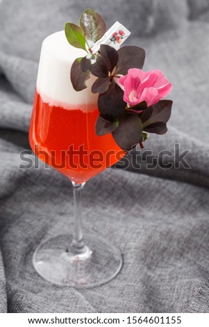 Homemade cocktail on red boulevard. glass with raspberry cocktail with raspberry alcohol with flowers on gray background. Overhead view, copy space. Advertising for cafe. Bar menu. Vertical photo.