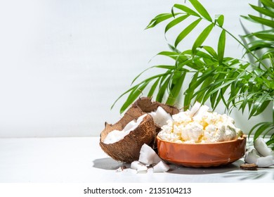 Homemade coconut cottage cheese. Vegan coconut non-dairy cottage cheese product, vegetarian diet  alternative calcium source, with palm tropical leaves and fresh coconut, white background copy space