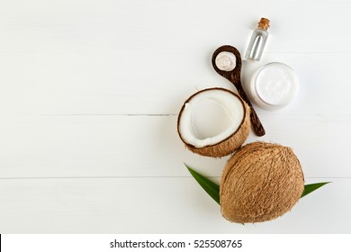Homemade coconut products on white wooden table background. Oil, scrub, milk and lotion from top view. Good for space and background.