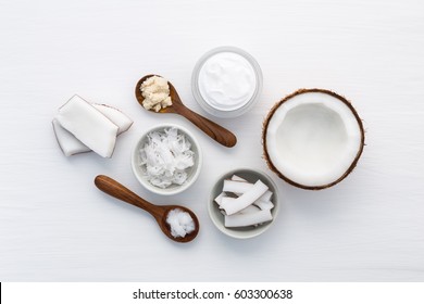 Homemade coconut products on white wooden table background. Oil, scrub, milk and lotion from top view. Good for space and background.