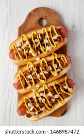 Homemade Coney Island Chili Dog With Onion And Mustard On A Rustic Wooden Board On A White Wooden Background, Top View. Flat Lay, Overhead, From Above.