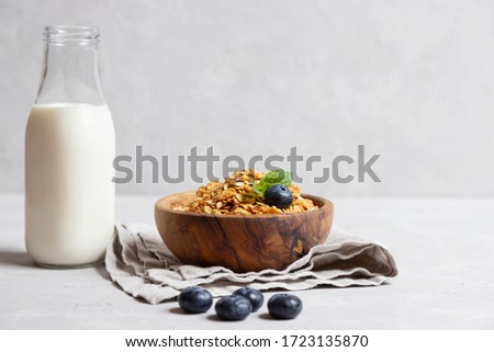 Homemade cooked healthy granola for breakfast in a wooden bowl on the table and near a bottle of milk. Place for text. Fitness food, snack