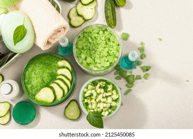 Homemade cosmetics with cucumber. Detoxification skin vegetable masks. Natural cream, sea salt, body lotion, and soap. Modern hard light, dark shadow. Stone concrete background, top view