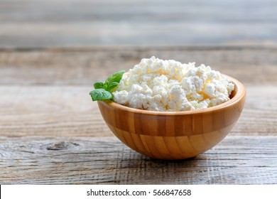 Homemade cottage cheese in a bowl on old wooden table.