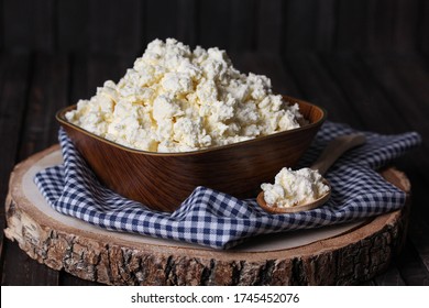 Homemade cottage cheese, curd in a wooden bowl on an old wooden background with a spoon. Rustic. Milk products. Background image, copy space