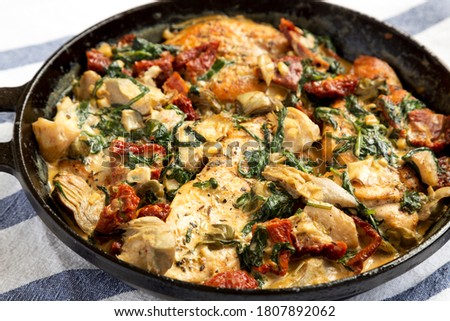 Homemade Creamy Tuscan Chicken in a cast iron pan, side view. Close-up.