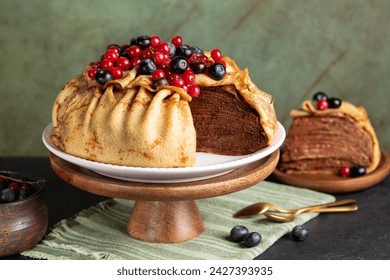 Homemade crepe cake, made of type of thin pancake and chocolate cream, decorated with blueberry and red currant, served on a dark table, green background. - Powered by Shutterstock