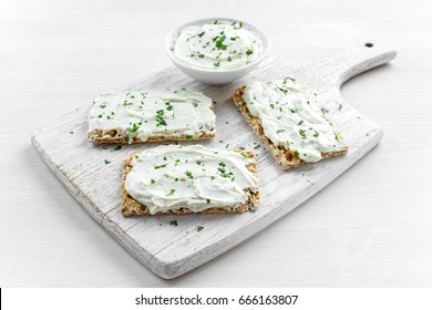 Homemade Crispbread toast with Cream Cheese and parsley on white wooden board background.