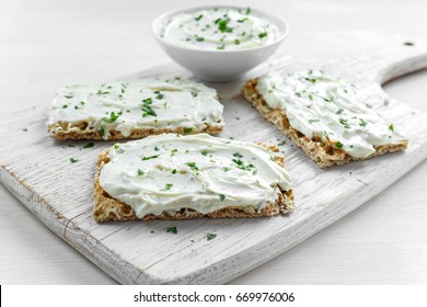 Homemade Crispbread toast with Cream Cheese and parsley on white wooden board background.