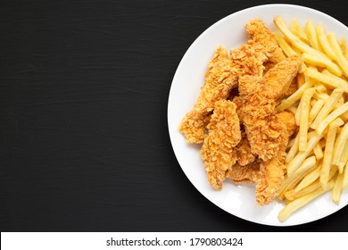 Homemade Crispy Chicken Tenders and French Fries on a white plate on a black background, top view. Copy space. - Shutterstock ID 1790803424