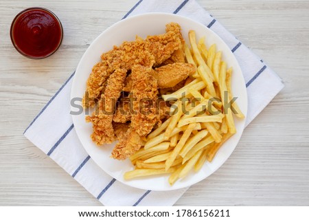 Homemade Crispy Chicken Tenders and French Fries on a white wooden background, top view. Flat  lay, overhead, from above.