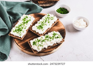 Homemade crispy rye bread with cottage cheese and green onions on a board