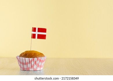 Homemade cupcake with Denmark flag on beige wood background. Holiday Independence Day. Danish flag decorates cakes.