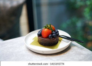 Homemade Dark Chocolate Cake With  Cookies Crust Pie, Topped With Fresh Strawberry, Blueberry On Marble Table And Blurred Background.