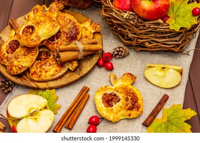 Homemade delicious apple dessert. Fresh sweet bakery, portioned puffs. Fragrant cinnamon sticks, ripe apples, autumn foliage, sea salt. Wooden boards table, close up