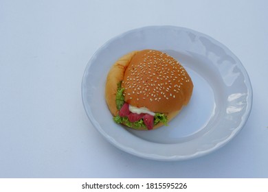 Homemade Delicious Burger Bread On White Plate. Fast Food And Junk Food Concept. It's Not Good For Health If Eat It Too Much. High Cholesterol. Risk To Be Obesity.