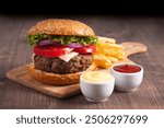 Homemade delicious hamburger with beef, onion, tomato, lettuce and cheese. Fresh burger close up on wooden rustic table with potato fries. Cheeseburger. Burger.