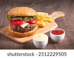 Homemade delicious hamburger with beef, onion, tomato, lettuce and cheese. Fresh burger close up on wooden rustic table with potato fries. Cheeseburger. Burger.