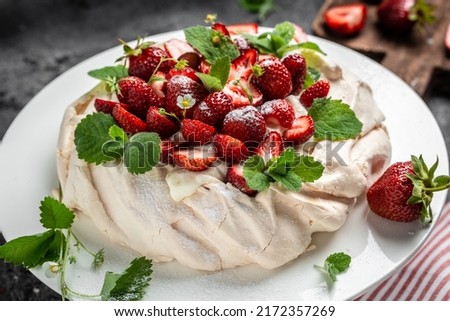 Homemade delicious meringue cake Pavlova with whipped cream, fresh strawberries and mint on wooden background, place for text, top view.