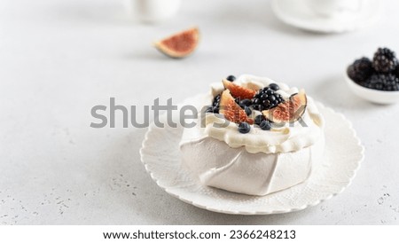 Homemade delicious meringue Pavlova cake with fresh blueberry, figs, blackberry and mascarpone on a white background. Copy space. Confectionery, recipe, menu. Meringue summer dessert