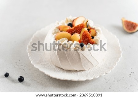 Homemade delicious meringue Pavlova cake with fresh blueberry, peach, figs and mascarpone on white background. Close up, side view. Confectionery, recipe, menu. Meringue summer dessert