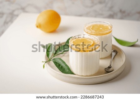 Homemade dessert panna cotta, mousse or pudding in a portion glass with lemon curd and fresh lemon.