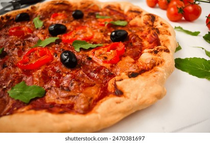 Homemade Diavola pizza with pepperoni, hot salami, cheese, tomato sauce, chili peppers, black olives, and basil on top. A traditional Italian meal with spicy salami, pepperoni, chili, and olives. - Powered by Shutterstock