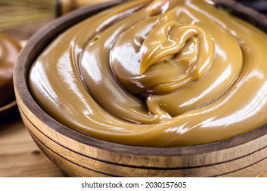 homemade dulce de leche, sour cream or doughy caramel in a rustic wooden bowl - Shutterstock ID 2030157605