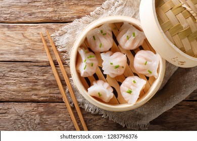 Homemade dumplings dim sum with stuffed shrimp close-up in a bamboo steamer box on the table. Horizontal top view from above